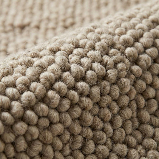 Handwoven chunky wool rug with neutral loop pile in farmhouse style interior setting