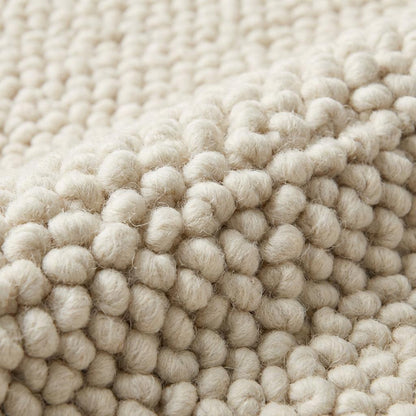 Handwoven chunky wool rug in neutral cream, showcasing thick texture and Scandinavian minimalist design