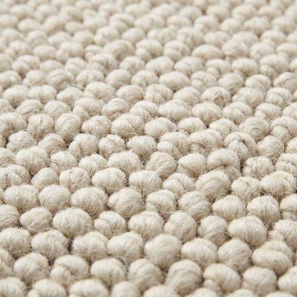 Handwoven chunky wool rug with textured loops in neutral cream tones for Scandinavian decor