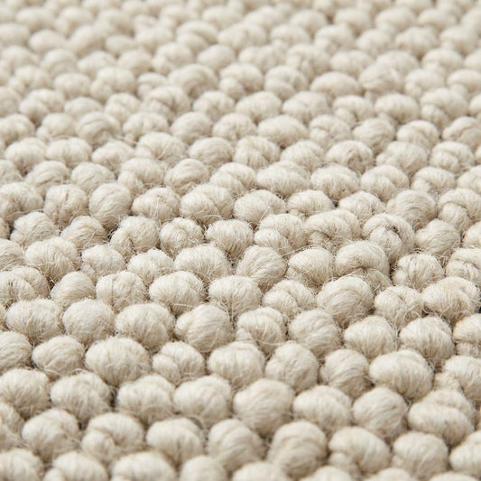 Handwoven chunky wool rug with textured loops in neutral cream tones for Scandinavian decor