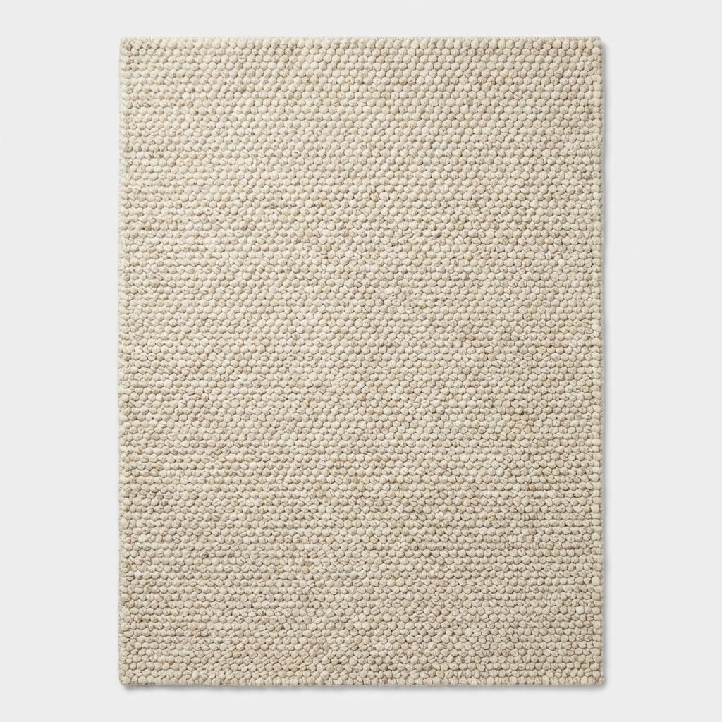 Handwoven chunky wool rug in neutral tones with textured looped surface for Scandinavian decor