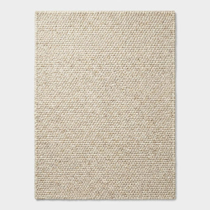 Handwoven chunky wool rug in neutral tones with textured looped surface for Scandinavian decor