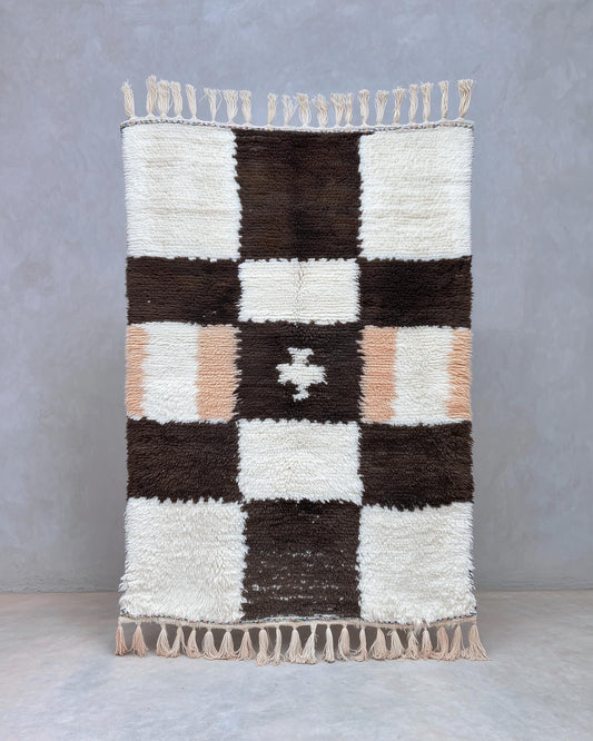 Handwoven Moroccan Berber shag rug with cream and chocolate checker pattern and peach accents, soft wool pile, and artisan fringe.