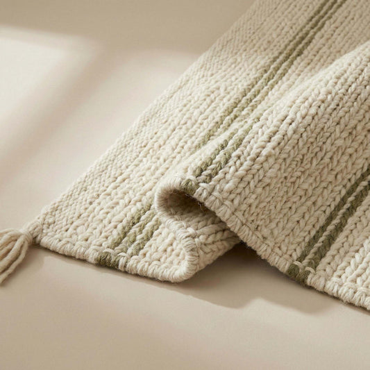 Handwoven wool area rug with chunky knit, cream base, green stripes, and tassels