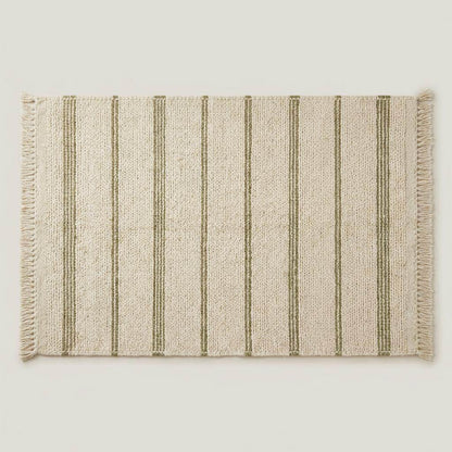 Handwoven wool area rug with chunky knit, green stripes, and tassels on neutral cream background