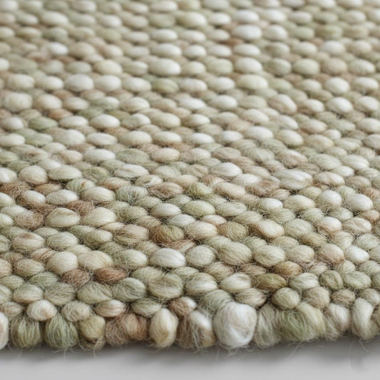 Handwoven wool pebble rug in sage green and cream with chunky textured loops for boho nursery or living room decor