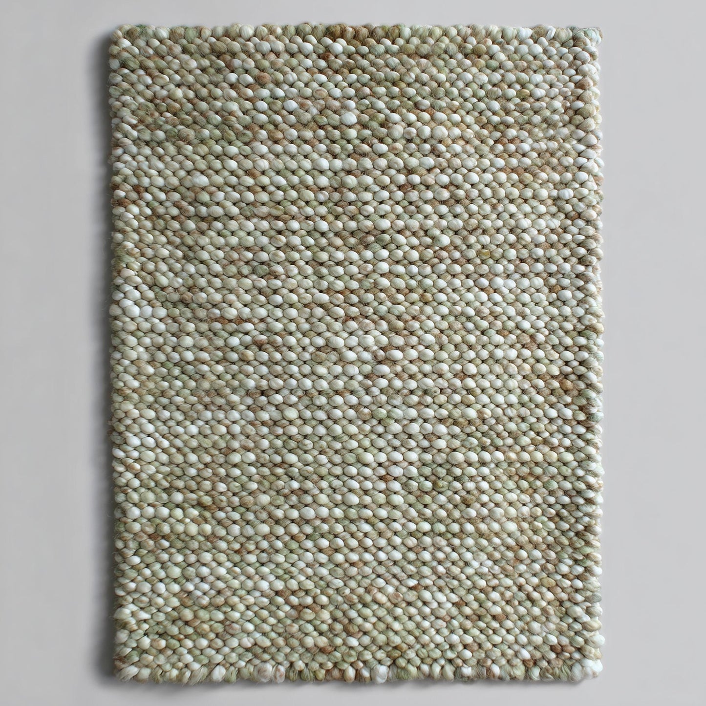 Top view of a handmade chunky wool rug with handwoven pebble texture in sage green, cream and tan — felted wool rectangle ideal for nursery or entryway.