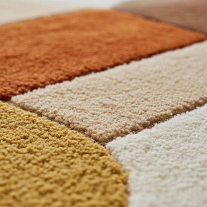 Mid century area rug with plush thick pile and geometric retro pattern in warm burnt orange, mustard yellow, and cream tones.