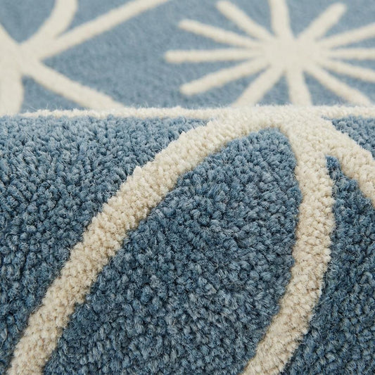 Close-up detail of plush blue and cream geometric rug showing raised tufted starburst pattern, dense fibers, and soft textured pile craftsmanship