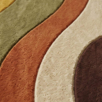 Earth tone abstract area rug with curved wavy shapes in mustard, olive and rust, styled in a sunny mid century living room with wood parquet floor and yellow chair.