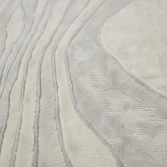 Close-up of tufted runner rug showing dense low-pile texture, soft fibers, carved wave lines, and matte neutral finish.