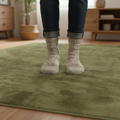 Minimalist Scandinavian style living room with light oak flooring and a deep olive green area rug providing colour and texture.