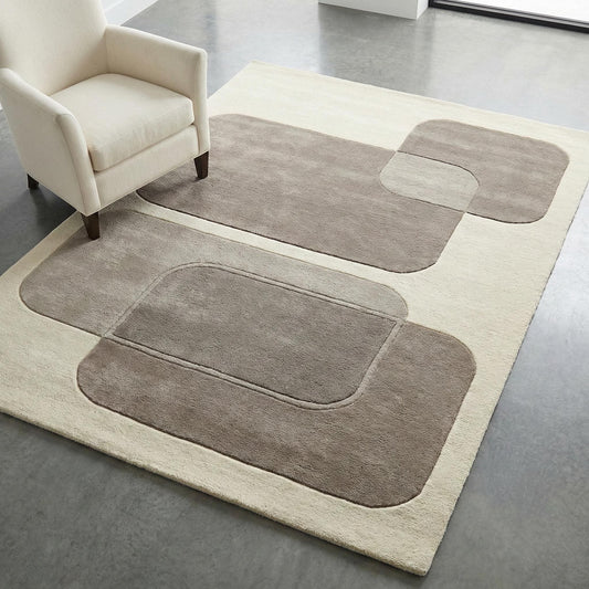 Modern abstract area rug in neutral tones styled under armchair in minimalist living room, plush geometric carpet with carved texture adding warmth and designer look to contemporary home décor.