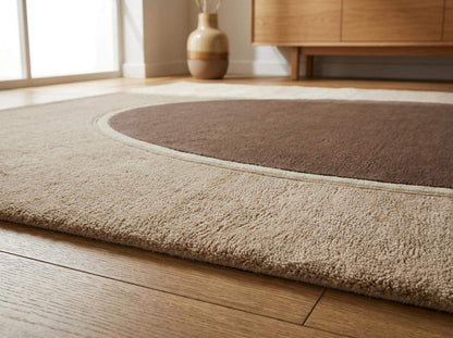 Modern neutral oval hand tufted wool area rug with soft beige and taupe tones in contemporary living room