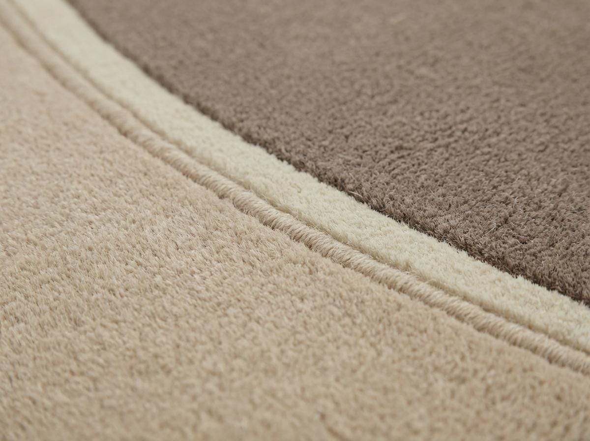 Modern neutral oval hand tufted wool area rug in beige and taupe tones in a contemporary living room