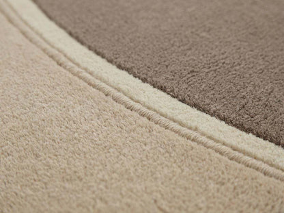 Modern neutral oval hand tufted wool area rug in beige and taupe tones in a contemporary living room