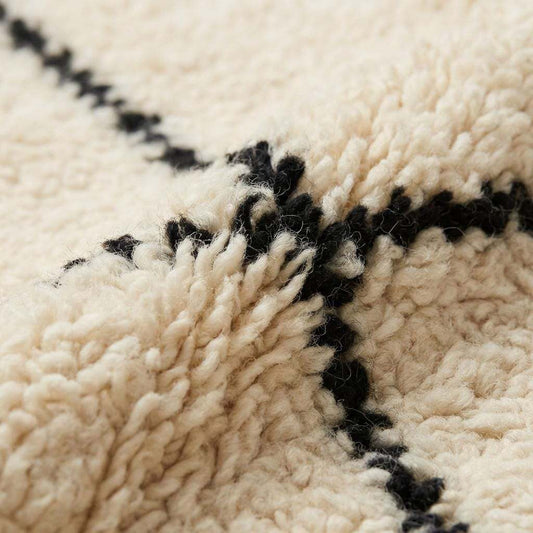 Close-up of plush ivory rug texture with black line pattern