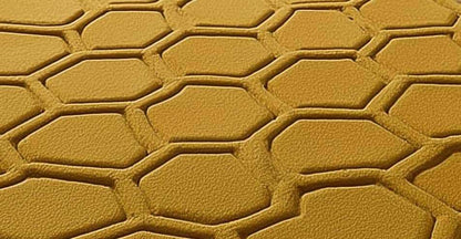 Mustard honeycomb rug with sculpted hexagon pattern on wood floor in entryway with potted plants