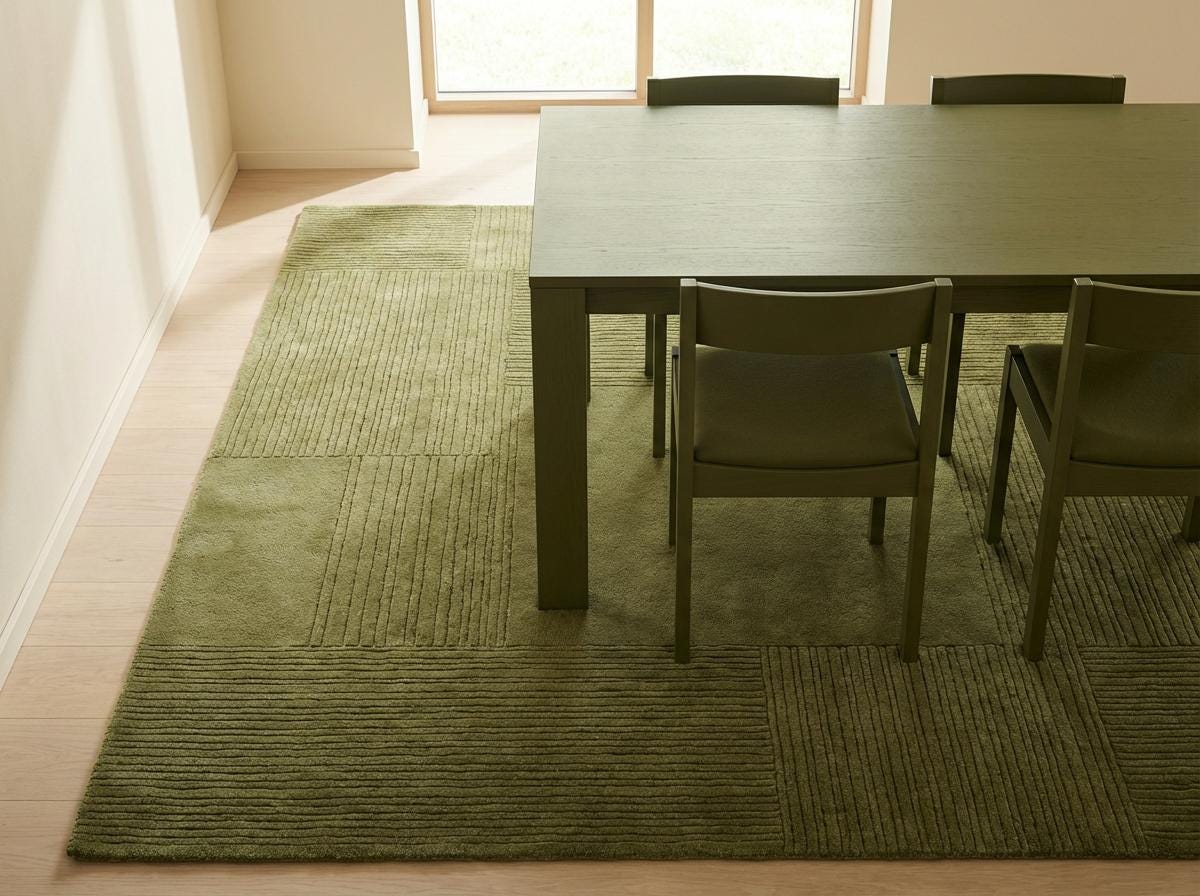 Corner detail of olive green textured area rug showing carved square pattern and clean finished edge