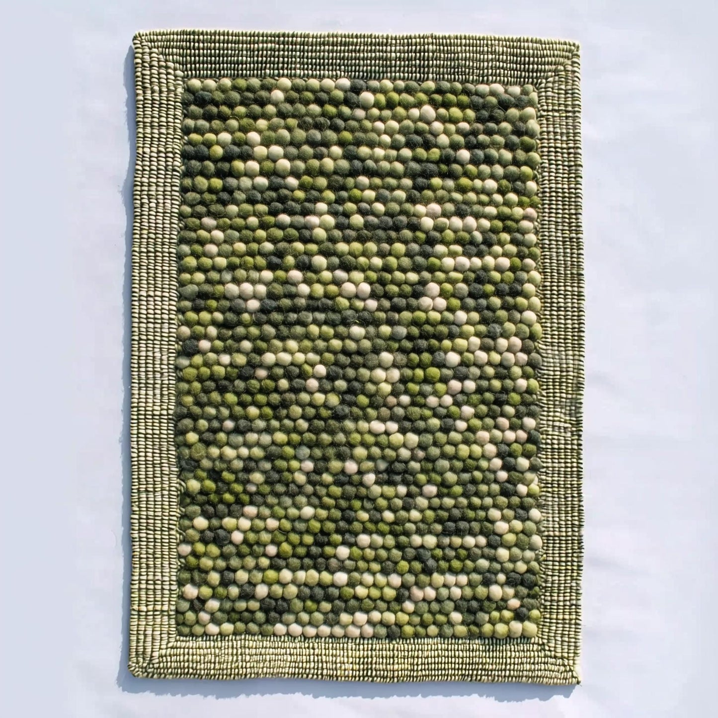 Handmade olive green felt ball rug with chunky wool texture for boho and Scandinavian home décor