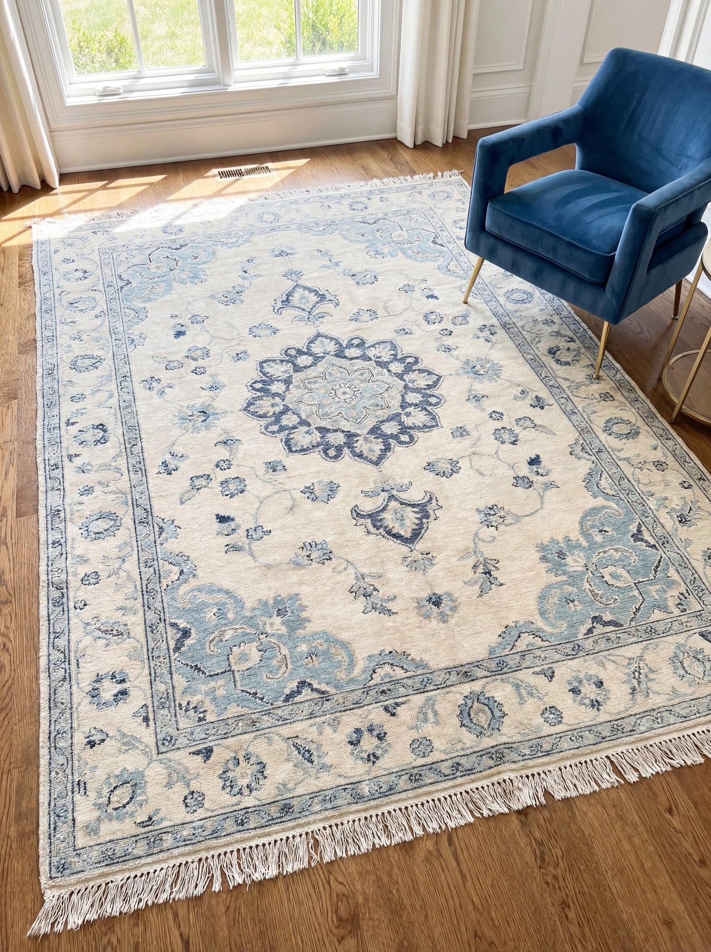 Oushak hand knotted rug with blue and ivory floral medallion design in a soft neutral living room setting