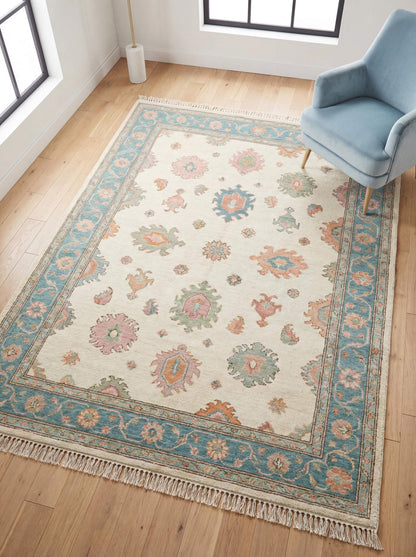 Hand knotted Oushak rug with pastel floral design, soft blue border and beige field in modern living room setting __etsy:7883142190