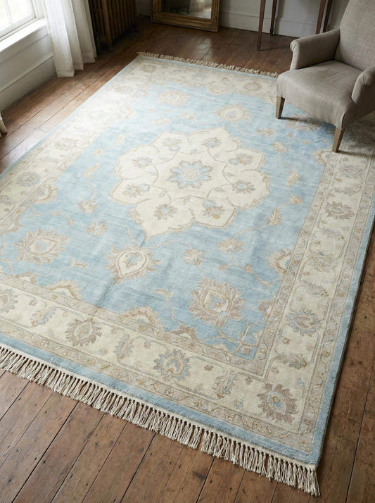 Hand knotted Oushak wool area rug in soft blue with traditional floral medallion design
