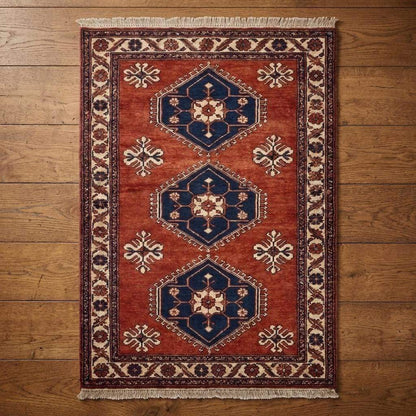 Rust red tribal hand knotted wool rug with geometric Kazak design in living room setting