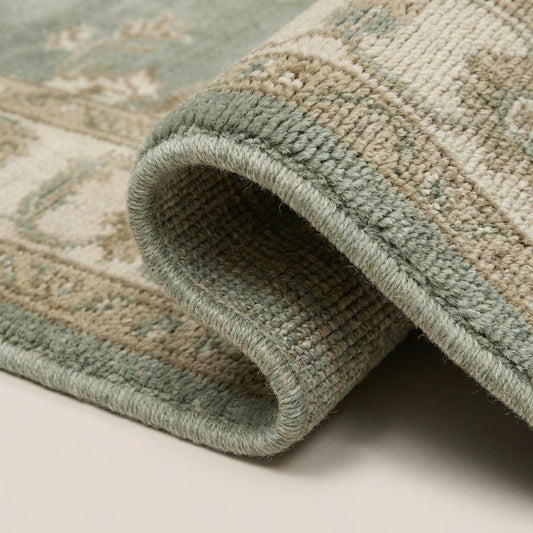 Close-up of hand knotted wool rug showing individual knots, soft natural wool fibers, and slightly textured pile surface