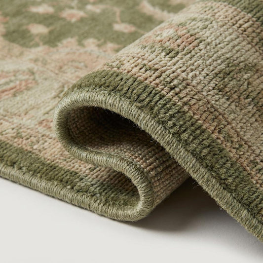 Close-up of dense hand-knotted wool pile showing individual knots, soft sage fibers, and subtle tonal variation