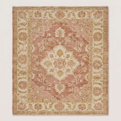 Blush pink and ivory Oushak style wool area rug with traditional floral motifs and faded vintage look