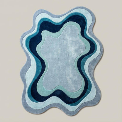 Organic shape abstract rug featuring layered blue waves styled on wooden flooring in a cozy contemporary home décor space.