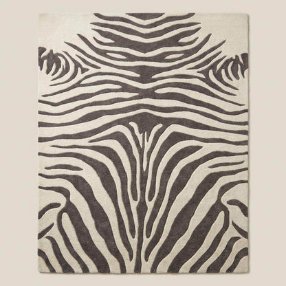Rectangular zebra pattern wool rug with bold animal print design styled under accent chair on light wood flooring.