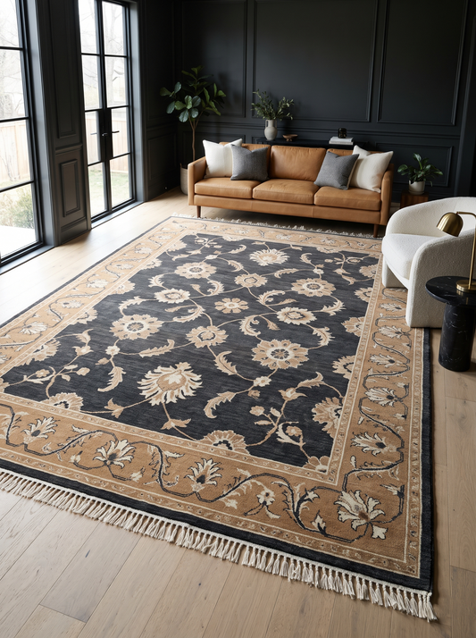 Charcoal Oushak Rug with ivory floral vines on a dark wool field, camel border, and hand-tied fringe