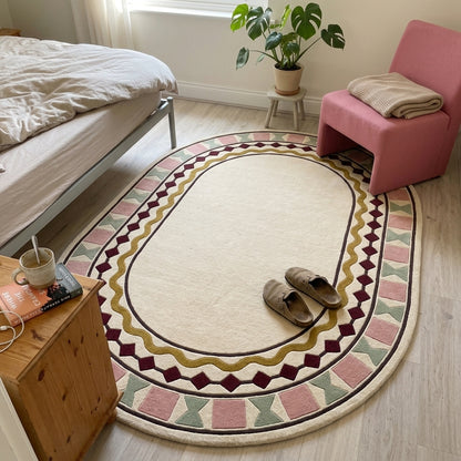 Ivory Oval Rug in hand-tufted wool with a plain ivory centre and a geometric border of burgundy diamonds, a mustard wavy line, blush squares and sage bowtie shapes - view 3