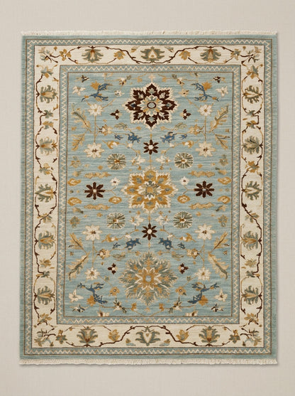 Blue Oushak Hand Knotted Wool Rug in muted blue with an ivory floral border, gold and brown palmette motifs and fringe.