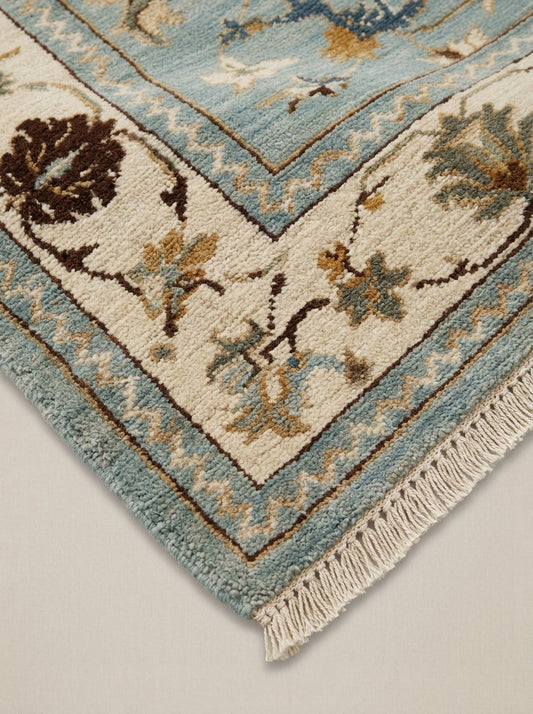 Blue Oushak Hand Knotted Wool Rug in muted blue and ivory, with floral palmette motifs, brown accents, and fringe.