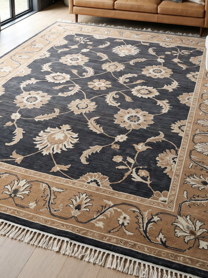 Charcoal Oushak Rug with a dark charcoal field, ivory and camel floral vines, wide camel border, and fringe