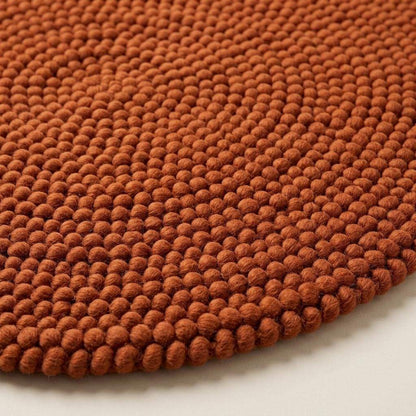 Handwoven chunky wool round rug in terracotta with braided knit texture for cozy modern boho decor