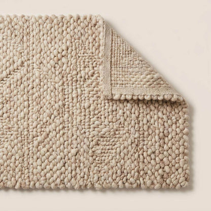 Handmade chunky wool rug with thick knit texture in neutral beige for cozy living room and bedroom decor