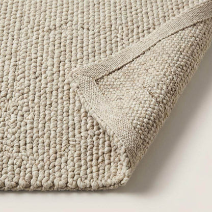 Handmade chunky wool rug with thick textured natural fibers in neutral tones for cozy minimalist decor
