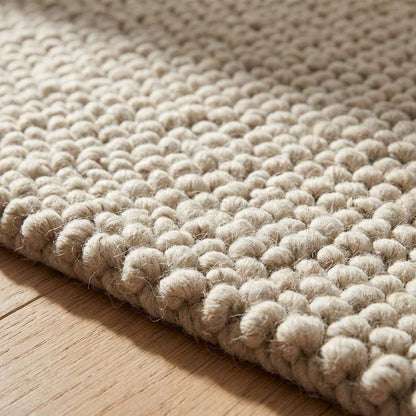 Handmade chunky wool rug with thick textured natural fibers in neutral tones for cozy minimalist living room decor