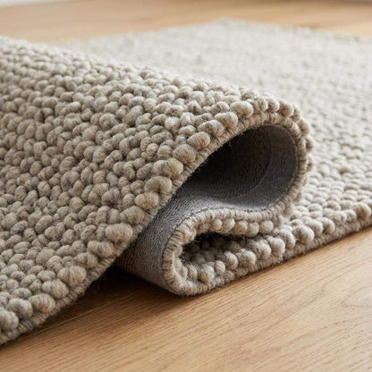 Chunky wool rug with handwoven pebble texture in neutral ivory tones for Scandinavian minimalist living room