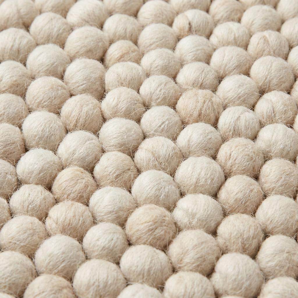 Handwoven chunky wool rug with neutral cream and beige felt balls in modern Scandinavian design