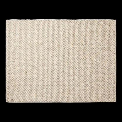 Handwoven chunky wool rug in neutral cream and beige tones with pebble texture, perfect for modern Scandinavian interiors
