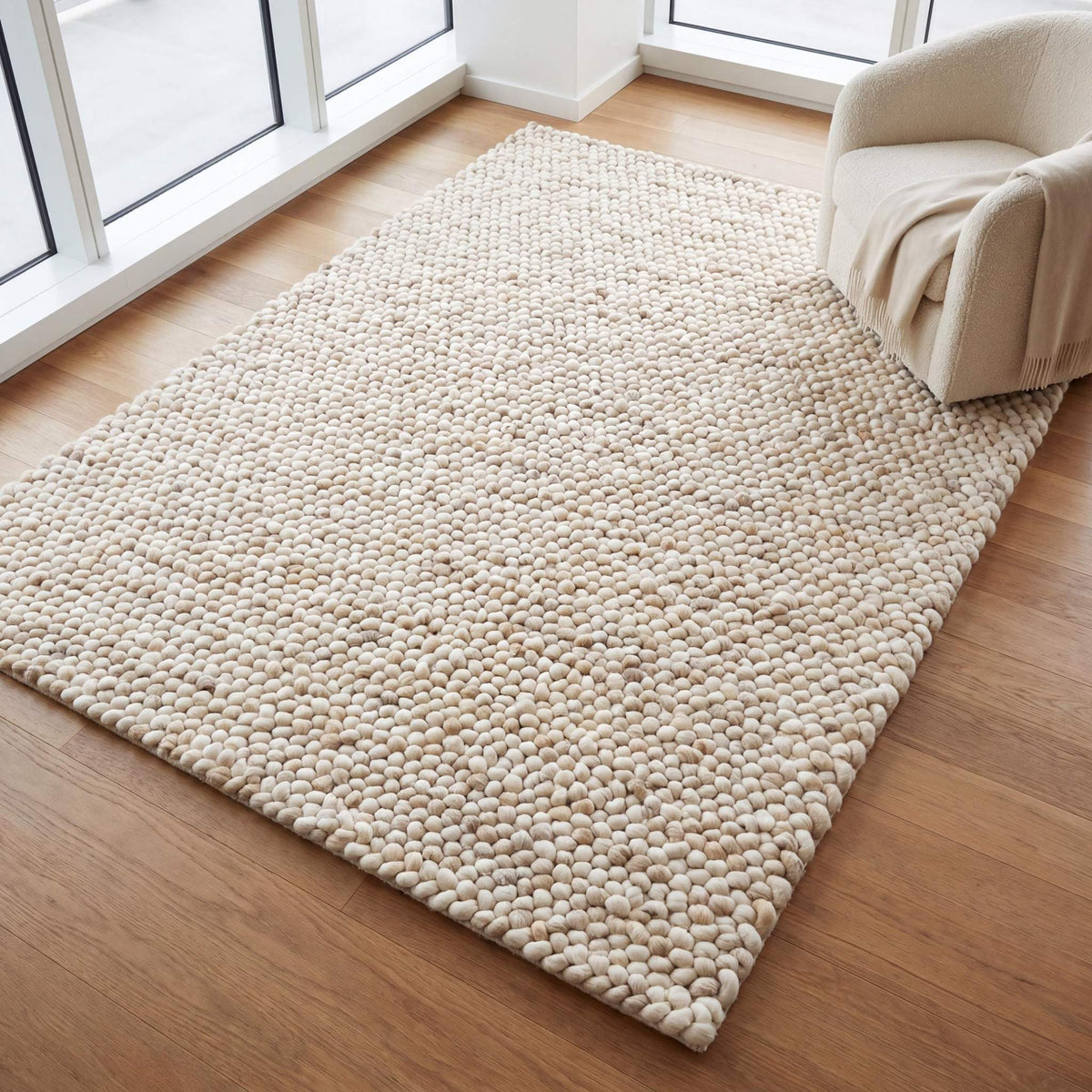 Handwoven chunky wool rug with neutral cream and beige felt balls for modern minimalist Scandinavian decor