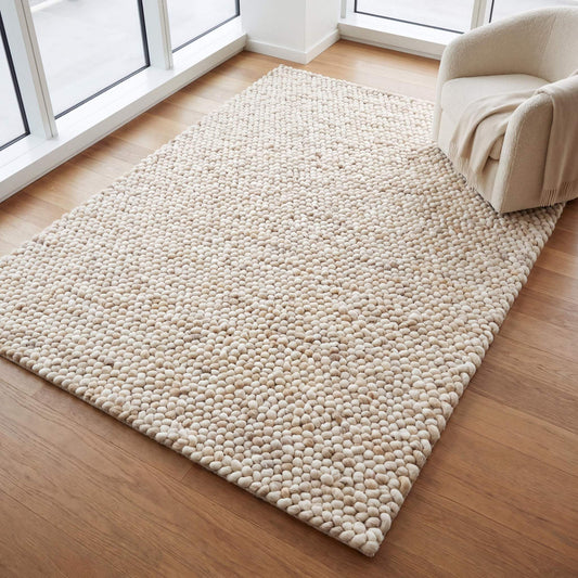 Handwoven chunky wool rug with neutral cream and beige felt balls for modern minimalist Scandinavian decor