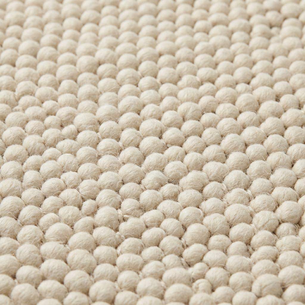 Handmade chunky wool rug with neutral tones in Scandinavian minimalist living room setting