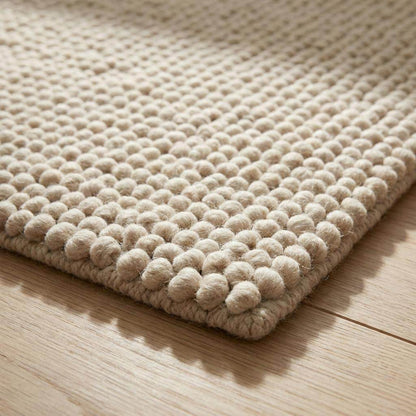Chunky wool rug with thick loop pile in neutral tones, handwoven for cozy, minimalist Scandinavian and farmhouse decor