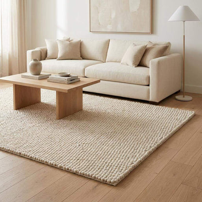 Handwoven chunky wool rug with neutral cream and beige felt balls in modern Scandinavian style